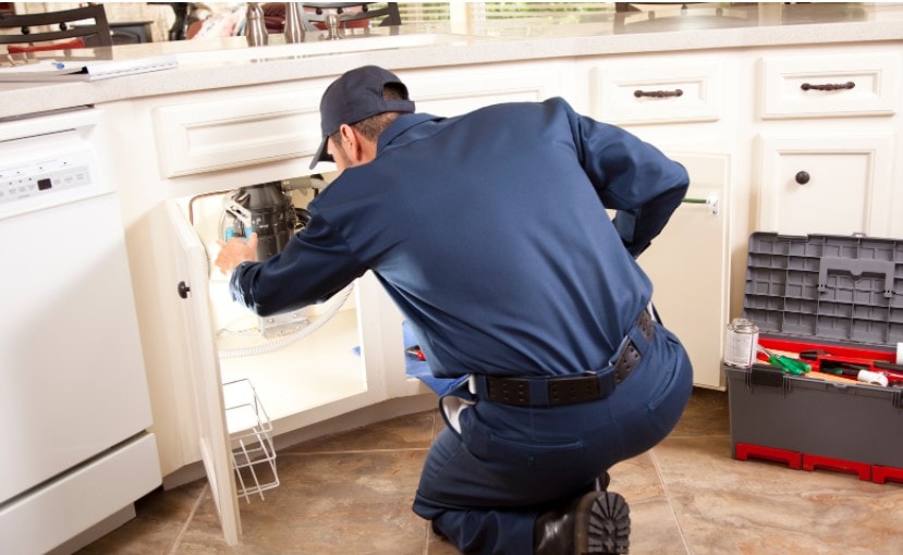 man dressed in unifrom fixing under the sink